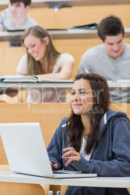 Girl sitting in lecture hall using laptop