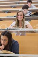 Student sitting at the lecture hall while smiling