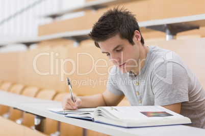 Student sitting reading a book and taking notes