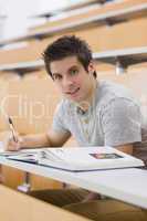 Student smiling while sitting and taking notes