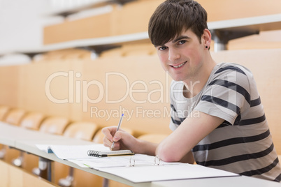 Student sitting at the lecture hall while holding a pen