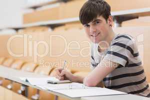 Student sitting at the lecture hall while holding a pen