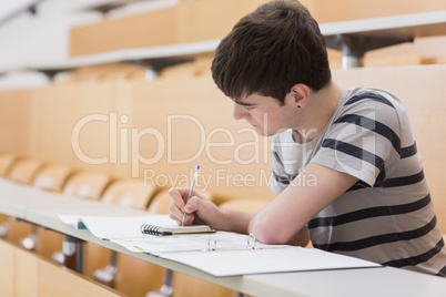 Man sitting at the lecture hall while writing