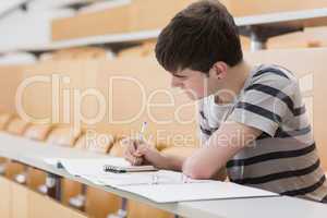 Man sitting at the lecture hall while writing