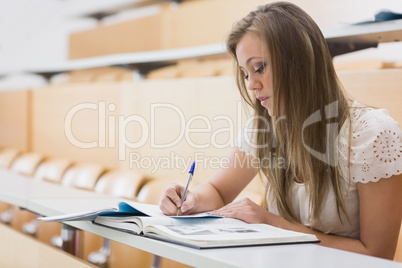 Concentrating woman sitting at the lecture hall writing