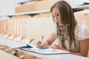 Concentrating woman sitting at the lecture hall writing