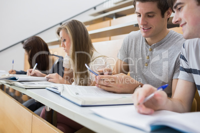 Student showing friend smartphone in lecture hall