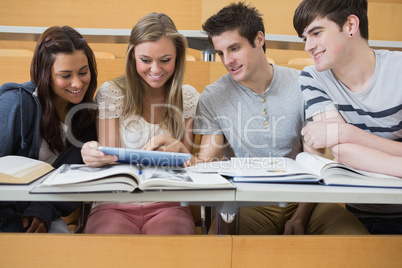 Students sitting looking at tablet pc and smiling