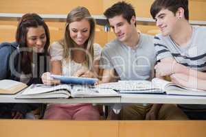 Students sitting looking at tablet pc and smiling