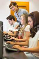 Students sitting at the computer with teacher looking on