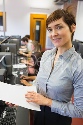 Teacher standing at the computer room holding papers