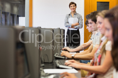 Teacher standing while students sitting at the computer