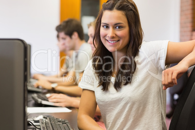 Student sitting at the computer room smiling