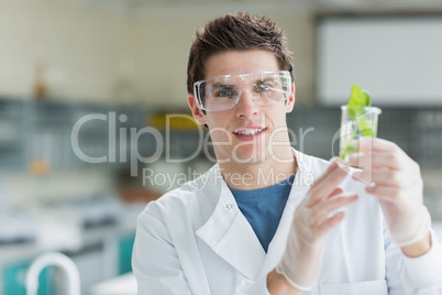 Student standing at the laboratory holding beaker with seedling