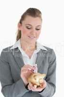 Businesswoman putting money in the piggy-bank