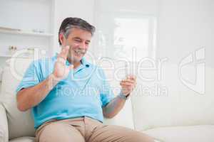 Smiling man waving at clear pane acting as digital tablet pc