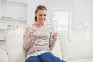 Woman holding a clear pane while smiling on the sofa