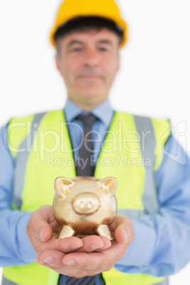 Smiling architect holding piggy bank