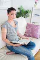 Woman sitting on the couch while holding a book