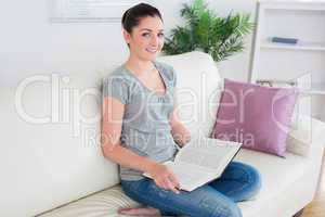 Woman sitting on the couch while holding the book