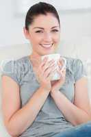 Smiling woman on the couch holding a mug