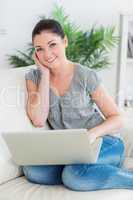 Smiling woman sitting on the couch and using a laptop