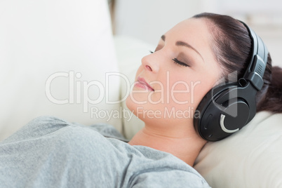 Relaxing woman lying on the couch and listening to music