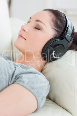 Young woman lying on the couch and listening to music