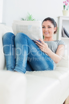 Woman lying on the couch reading a newspaper