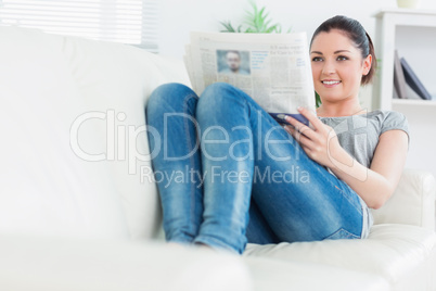 Relaxing woman lying on the couch and reading newspaper