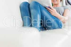 Woman lying on the couch and reading newspaper