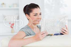 Smiling woman sitting on the couch and reading newspaper