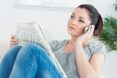 Phoning woman sitting on the couch and reading the news