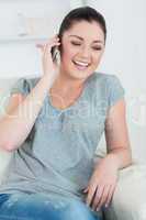 Laughing woman telephoning and sitting on the couch