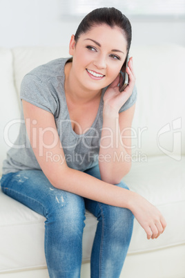 Smiling woman phoning and sitting on the couch