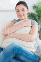 Woman sitting on the couch hugging a pillow