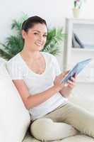 Happy woman on the couch using a tablet pc