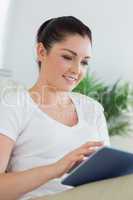 Smiling woman using a tablet pc while being in a living room