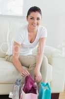 Woman sitting on a couch and taking new clothes out of bags