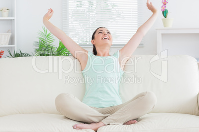 Carefree woman sitting on the couch and stretching
