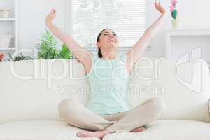 Carefree woman sitting on the couch and stretching