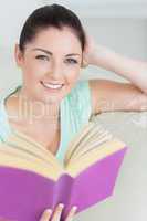 Woman holding a book while sitting on the couch