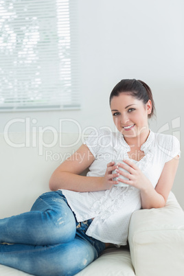 Woman lying in the couch holding a mug