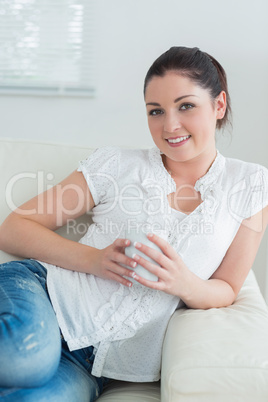 Smiling woman lying on the couch and holding a cup