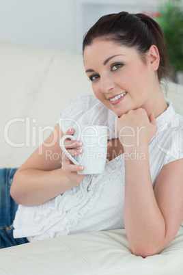 Lying woman on the couch holding a mug