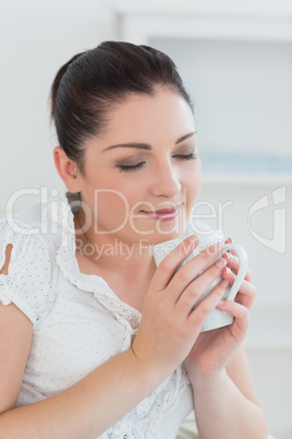 Woman sitting on the couch smelling the coffee