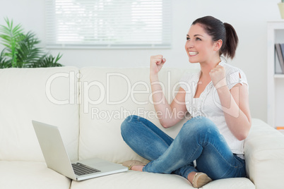 Woman using a laptop on the couch and being happy