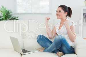 Woman using a laptop on the couch and being happy