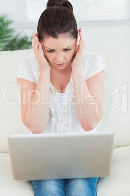 Overwhelmed woman on the couch using a laptop