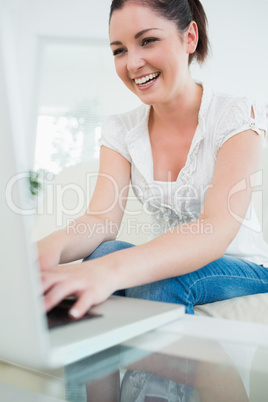 Laughing woman on the couch using a laptop